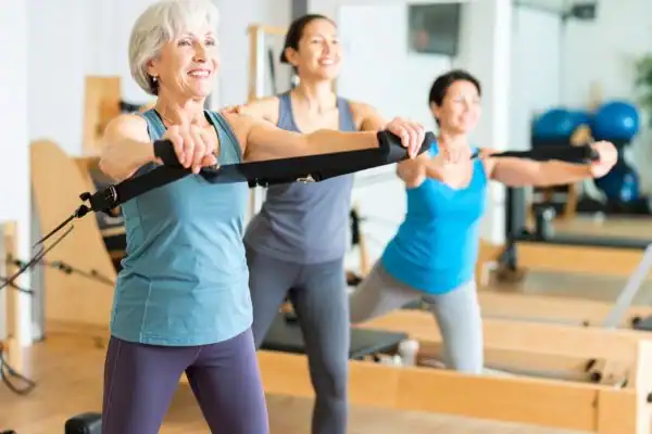 Toning Arms After 60: Empowering Womens Fitness Through Effective Weight Training 2 older woman doing weight training East Kilbride and resistance in the gym to tone upper arms