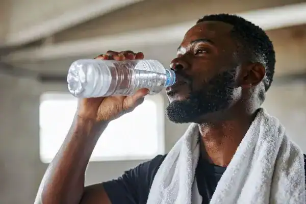 Image of man drinking water to improve hydration East Kilbride after work out.